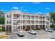 Three-story building with brick accents, stairs and white railings, and parking with several cars at 1058 Sea Mountain Hwy. # 9-101, North Myrtle Beach, SC 29582