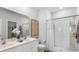 Modern bathroom featuring double sinks, a large mirror, and a shower with white tile surround at 1170 Silver Perch Place, Sunset Beach, NC 28468