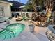 Backyard with a stone waterfall, hot tub, and outdoor dining area at 1504 Saint Thomas Circle, Myrtle Beach, SC 29577