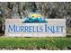 Large welcome sign to Murrells Inlet, Seafood Capital of South Carolina, set against scenic greenery at 323 Waties Dr., Murrells Inlet, SC 29576