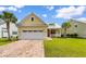 Inviting yellow home with brick driveway, a pristine garage, and lush green lawn under a bright blue sky at 323 Waties Dr., Murrells Inlet, SC 29576