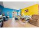 Bright living room with blue and yellow walls, patterned couches, and light wood flooring at 348 Hidden Cove Dr., Little River, SC 29566