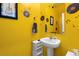 Bright half bath with yellow walls, vinyl record art, and a pedestal sink at 348 Hidden Cove Dr., Little River, SC 29566