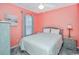 Bedroom featuring salmon-colored walls, a bed with white bedding, and gray furniture at 404 1St Ave. N # H, North Myrtle Beach, SC 29582