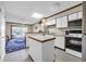 Kitchen with white appliances, white cabinets, breakfast bar, neutral flooring and a living room view at 4350 Intercoastal Dr. # 2402, Little River, SC 29566