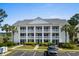 Inviting condo exterior featuring multiple balconies, lush landscaping, and ample parking spaces at 4940 Windsor Green Way # 301, Myrtle Beach, SC 29579
