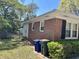 Back of red brick home with trash cans and an enclosed yard at 505 1St Ave. S, North Myrtle Beach, SC 29582
