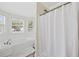 Bright bathroom featuring a soaking tub, bay windows with a view, and a white shower curtain at 62 Warbler St., Georgetown, SC 29440