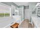 Bathroom featuring a soaking tub, glass shower enclosure, double sinks, and decorative sconces at 67 Camden Circle, Pawleys Island, SC 29585