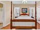 Cozy bedroom featuring wood floors, a four poster bed, and bright windows dressed with sheer white curtains at 67 Camden Circle, Pawleys Island, SC 29585