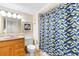 Bathroom with oak vanity, toilet, tub, and blue, gold, and white geometric pattern shower curtain at 9820 Queensway Blvd. # 804, Myrtle Beach, SC 29572