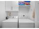 Bright laundry room features washer, dryer, cabinet, and shelving space perfect for storage at 108 N Oak Dr., Surfside Beach, SC 29575