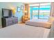 Well-lit bedroom features two beds and a lovely chair by the bright balcony window at 1501 S Ocean Blvd. # 1410, Myrtle Beach, SC 29577
