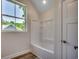 Bright bathroom featuring a bathtub and shower combination, with a window that overlooks leafy green trees at 1673 Carriage Ln., Little River, SC 29566