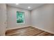 A minimalist bedroom with light walls, wooden floors, and a window view of lush greenery at 1673 Carriage Ln., Little River, SC 29566