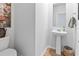 Compact powder room with a pedestal sink, decorative mirror, and hardwood floors at 205 Marsh Deer Place, Surfside Beach, SC 29575