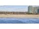 Beachfront view of condos along a sandy shoreline with ocean waves and a bright blue sky at 210 N Ocean Blvd. # 333, North Myrtle Beach, SC 29582