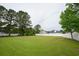 Expansive backyard with lush green grass and mature trees, enclosed by a white fence at 249 Ashepoo Creek Dr., Myrtle Beach, SC 29579