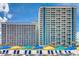 Oceanfront resort with a beach view featuring blue and yellow umbrellas, chairs, and clear skies at 3000 N Ocean Blvd. N # 129, Myrtle Beach, SC 29577