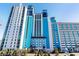 A multi-story resort with a bright blue and white exterior, palm trees, and well-maintained landscaping at 3000 N Ocean Blvd. N # 129, Myrtle Beach, SC 29577