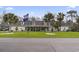 Expansive single story home featuring dormer windows, a covered porch, manicured lawn, mature palms, and American and State flags at 390 Boundary Ave., Murrells Inlet, SC 29576