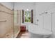 Bright bathroom featuring a soaking tub, glass-enclosed shower, and a window with wood shutters, exuding a spa-like ambiance at 444 Dornoch Dr., Pawleys Island, SC 29585