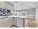 Stylish kitchen with white cabinets, quartz countertops and mosaic backsplash opening to dining area at 4705 Wild Iris Dr. # 305, Myrtle Beach, SC 29577