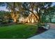 Beautiful home at dusk, framed by Spanish moss laden trees, with manicured lawn, and inviting outdoor lighting at 509 Heston Point Dr., Pawleys Island, SC 29585