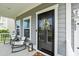 Inviting covered porch featuring rocking chairs, a lantern, and a black front door with decorative wreath at 5605 Whitebark Dr., Myrtle Beach, SC 29577