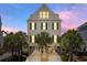 Lovely stilted home featuring bright windows and dark shutters, surrounded by lush palm trees, creating a tropical paradise at 703 S Waccamaw Dr., Garden City Beach, SC 29576