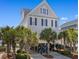 Charming stilted home with palm trees offers coastal living at its finest with dark blue shutters and beach views at 703 S Waccamaw Dr., Garden City Beach, SC 29576