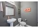 Half bath features a pedestal sink, toilet, decorative mirror and gray walls at 750 Howard Ave. # C, Myrtle Beach, SC 29577