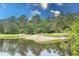 Scenic golf course view with a water hazard and sand trap, framed by lush trees under a bright blue sky at 750 Pinehurst Ln. # 84A, Pawleys Island, SC 29585