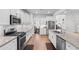 Well-appointed kitchen with white cabinetry, granite countertops, stainless steel appliances, and wood flooring throughout at 818 Mourning Dove Dr., Myrtle Beach, SC 29577