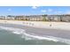 Expansive beach view with ocean waves, sunbathers, and attractive condominiums in the background on a sunny day at 917 S Ocean Blvd. # 103, Surfside Beach, SC 29575