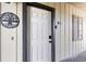 Unit 103 entrance featuring a white door with black hardware, a 'surfside retreat' decorative ornament, and a small window at 917 S Ocean Blvd. # 103, Surfside Beach, SC 29575