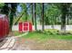 Backyard view of a red shed, surrounded by grass, trees, and a white fence at 1205 King St., Myrtle Beach, SC 29577