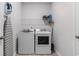 Well-lit laundry room with modern washer and dryer units, shelving, and a door at 179 Empyrean Circle, Myrtle Beach, SC 29588