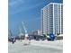 A lively beach scene with parasail flags, sunbathers, and an oceanfront condo tower in the background at 1801 N Ocean Blvd. # Q-2, North Myrtle Beach, SC 29582