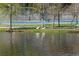 Water view of a tennis court, lush greenery, ducks, and a tennis player on the court at 1801 N Ocean Blvd. # Q-2, North Myrtle Beach, SC 29582
