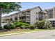 Exterior view of a condo with multiple balconies, showcasing lush landscaping and mature trees at 202 Maison Dr. # L-301, Myrtle Beach, SC 29572
