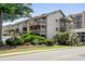 Exterior view of a condo with multiple balconies, showcasing lush landscaping and mature trees at 202 Maison Dr. # L-301, Myrtle Beach, SC 29572