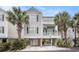 Desirable raised beach home featuring neutral siding, open carport, and lush landscaping with mature palms at 212 Millwood Dr., Surfside Beach, SC 29575