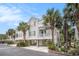 Inviting raised beach home showcasing a covered balcony, lush palms, and convenient drive-under parking at 212 Millwood Dr., Surfside Beach, SC 29575