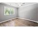Bright bedroom with neutral paint, hardwood floors, and a window with leafy green outdoors view at 2415 Magnolia Lane, Little River, SC 29566