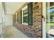 Close-up view of the brick facade, showing the house number, front door, and decorative shutters at 2415 Magnolia Lane, Little River, SC 29566