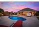 Inviting outdoor pool area with brick home, outdoor kitchen, and lounge area under a colorful dusk sky at 310 Babylon Pine Dr., Myrtle Beach, SC 29579