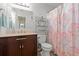 Well-lit bathroom with vanity, toilet, shower with patterned curtain, and decorative shelving unit at 314 Lyons Cove Dr., Myrtle Beach, SC 29577