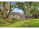 Brick home with a screened-in porch and well-maintained lawn, under mature trees at 423 Chapman Loop, Pawleys Island, SC 29585