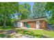 Back exterior view of a brick home with a patio and mature trees at 4300 Crows Nest Ct., Myrtle Beach, SC 29579